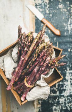 Mevsimlik hasat üretmek. Taze çiğ çiğ mor kuşkonmaz ahşap tepsi arka plan üzerinde