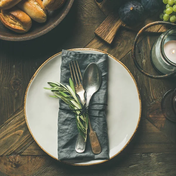 秋天的节日表装饰设置 与亚麻餐巾 叉子和勺子 在服务上的新鲜水果板板 面包馒头 橄榄树枝在木制的背景 — 图库照片