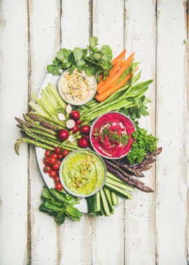 Sağlıklı yaz vegan tabak yemek saati. Nohut, pancar, ıspanak humus dips Beyaz ahşap zemin üzerinde taze sebze ile