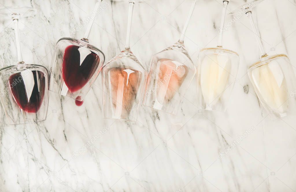 red, rose and white wine in glasses and corkscrews over grey marble background