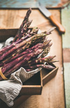 Mevsimlik hasat üretmek. Taze çiğ çiğ mor kuşkonmaz rustik ahşap tepsi arka plan üzerinde
