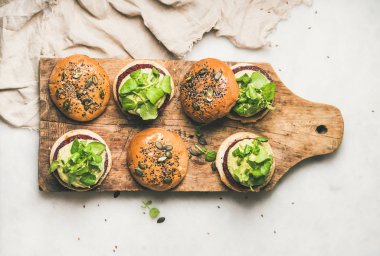 Sağlıklı vejetaryen burger quinoa pancar köftesi ile ahşap tahta üzerinde avokado krem ve yeşil lahanası