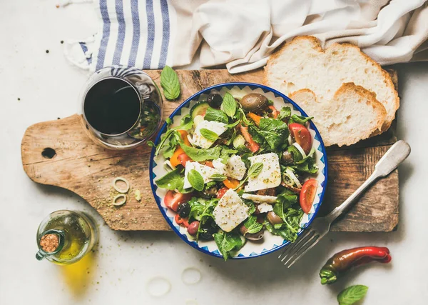 传统希腊沙拉配羊乳酪 瓶装橄榄油 橄榄色和红葡萄酒 白色大理石桌上质朴的木制服务板 — 图库照片