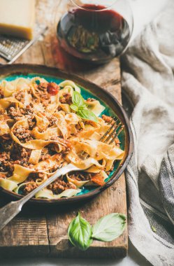 İtalyan geleneksel makarna yemek. Tagliatelle bolognese kıyma, domates sosu ve parmesan peyniri ve rustik ahşap tahta arka plan, seçici odak üzerinde kırmızı şarap ile