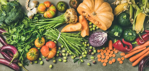 Healthy vegetarian seasonal Fall food cooking background. Flat-lay of Autumn vegetables and herb from local market over grey concrete background, top view. Clean eating, alkaline diet food