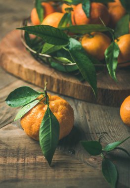 Noel ve yeni yıl tablo. Rustik ahşap masa arka plan, seçici odak, dikey kompozisyon gemide tepsisinde yaprakları ile taze olgun mandalina