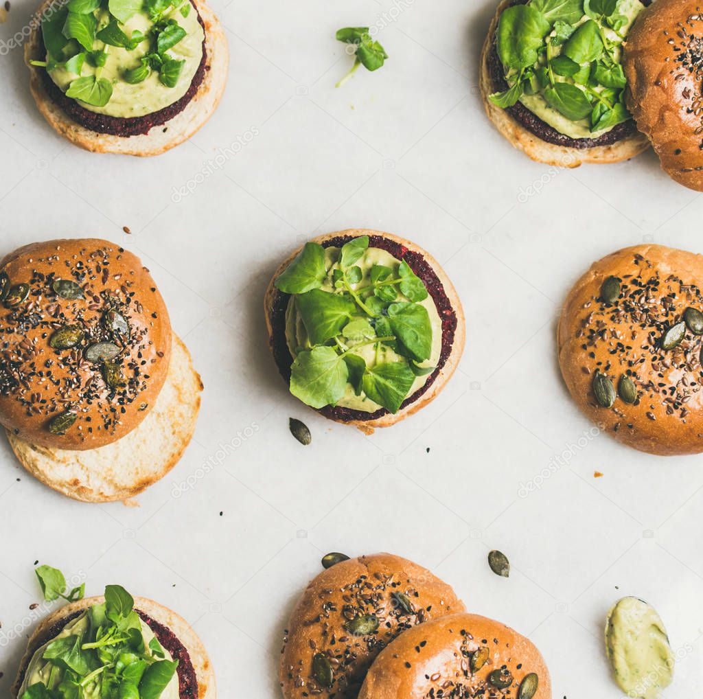 Flat-lay of healthy vegan burgers with quinoa beetroot patties, avocado cream and green sprouts over light background, top view . Vegetarian, clean eating food