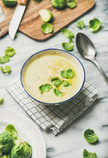 Seasonal brussels sprouts vegetable cream soup in bowl and fresh green brussel sprouts over grey marble background, vertical composition. Vegan, vegetarian, healthy, dieting food concept — Stock Image Seasonal Brussels Sprouts Vegetable Cream Soup Bowl Fresh Green Brussel Stock Photo