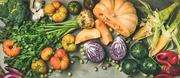 Healthy vegetarian seasonal Fall food cooking background. Flat-lay of Autumn vegetables and herb over grey concrete background, top view, copy space, wide composition. Clean eating, alkaline diet food