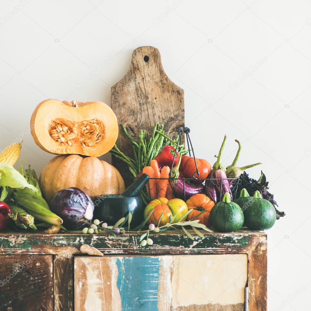 Fall vegetarian food ingredient variety. Assortment of Autumn vegetables for healthy cooking over rustic cupboard, white wall background, copy space, square crop. Local market organic produce