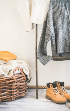 Sonbahar ya da kış sıcak Triko askı, beyaz duvar arka plan üzerinde. Şık kadın kış giyim. Yün kazak, çizme ve örme şapka