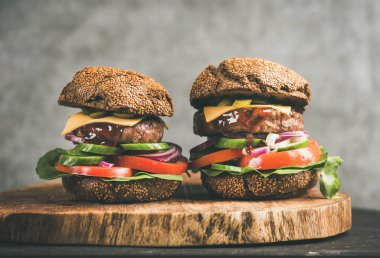 Sığır eti çizburger rustik ahşap masa, arka plan, gri beton duvara Barbekü sosu ile yakın çekim. Konfor gıda, burger bistro kavramı