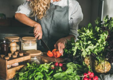 Mevsimlik Vejetaryen, vegan yemek düşer. Keten önlük kesme taze domates beton mutfak tezgahı üzerinde kadın. Yavaş gıda, comfort gıda, sağlıklı beslenme, beslenme temiz