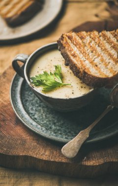 Sonbahar, kış eve akşam yemeği. Sonbahar Kupası ve tost krem kereviz çorbası üzerinde sarı keten masa örtüsü, ısınma yakın çekim. Konfor gıda, vegan, Vejetaryen, sağlıklı ve yavaş gıda kavramı