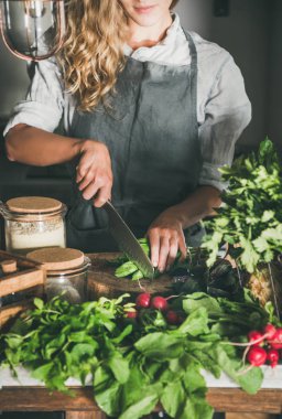 Mevsimlik Vejetaryen, vegan yemek düşer. Kadın keten önlük yeşil sebze malzemeler beton mutfak tezgahına kesme. Yavaş gıda, comfort gıda, sağlıklı beslenme, beslenme temiz