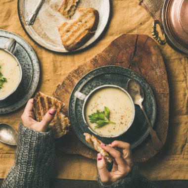 Sonbahar, kış eve akşam yemeği. Düz-lay ekmek ile kereviz krem çorba ve erkek el ısınma keten masa örtüsü, üstten görünüm, kare kırpma düşme. Konfor gıda, Vejetaryen, sağlıklı ve yavaş gıda kavramı