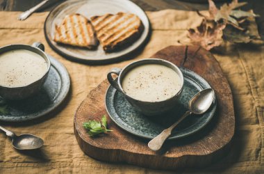 Sonbahar, kış eve akşam yemeği. Kereviz krem çorba bardak ve kızarmış ekmek üzerinde sarı keten masa örtüsü ısınma düşmek. Konfor gıda, vegan, Vejetaryen, sağlıklı ve yavaş gıda kavramı