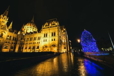 Budapeşte, Macaristan - Aralık, 2017. Bina ve akşamları süslenen mavi tatil ışıkları Noel ağacı içinde ünlü Meclis