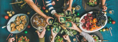 Festival masada Noel ve yeni yıl partisi yemek için toplama arkadaş şirket. Düz-lay insan eller gözlük içecekler ile tutarak, tatil birlikte kutluyor, üstten görünüm, geniş kompozisyon