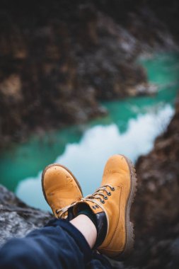 Gezgin veya vahşi doğa Gezgini uçurum ile dağ nehir Kanyon'da arka plan üzerinde sarı kirli hiking Çizmeli metrelik. Seyahat, turizm, yolculuk tutkusu veya macera kavramı