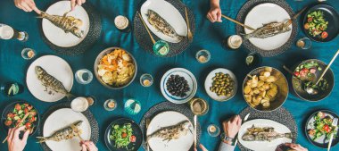 Balık ve cips bira partisi toplama, yeme ve içme birlikte arkadaşlar. Düz-lay insan eli, bira gözlük, ızgara levrek balık, sebze salatası, kavrulmuş patates ve cips, geniş kompozisyon