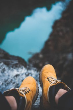 Gezgin veya vahşi doğa Gezgini sarı kirli hiking içinde metrelik uçurum dağ nehir Kanyon'da arka plan, seçici odak ile üzerinde oturan botlar. Seyahat, turizm, yolculuk tutkusu veya macera kavramı
