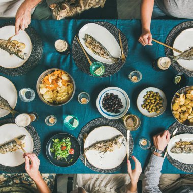 Balık ve cips bira partisi toplama, yeme ve içme birlikte arkadaşlar. Düz-lay insan eli, bira gözlük, ızgara levrek balık, sebze salatası, kavrulmuş patates ve cips, kare kırpma