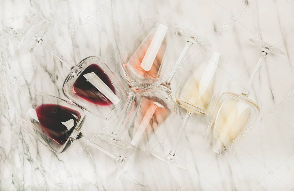 Flat-lay of red, rose and white wine in glasses over grey marble background, top view. Bojole nouveau, wine bar, winery, wine degustation concept