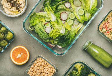 Cam konteynerlerde sağlıklı vegan yemekler. Yassı sebze salataları, bakliyat, fasulye, lahanası, humus ve beton tablo üzerinde şişe taze meyve suları, üst görünüm. Bahar menüsü, kilo kaybı gıda