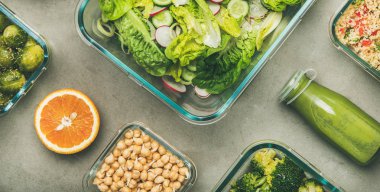 Cam konteynerlerde sağlıklı vegan yemekler. Yassı sebze salataları, bakliyat, fasulye, lahanası, humus ve beton tablo üzerinde şişe taze meyve suları, üst görünüm, geniş kompozisyon. Kilo kaybı gıda