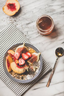Sağlıklı kahvaltı. Beyaz mermer arka planda, üst görünüm üzerinde çilek, incir, şeftali, Chia tohumları ve bal ile Yunan yoğurt granola kase düz-Lay. Vejetaryen, diyet, detoks gıda konsepti
