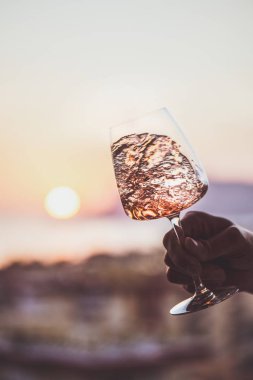 Deniz manzarası ve arka planda güzel gün batımı, yakın çekim ile Mans el gül şarap bardak. Yaz akşamı rahat ruh kavramı
