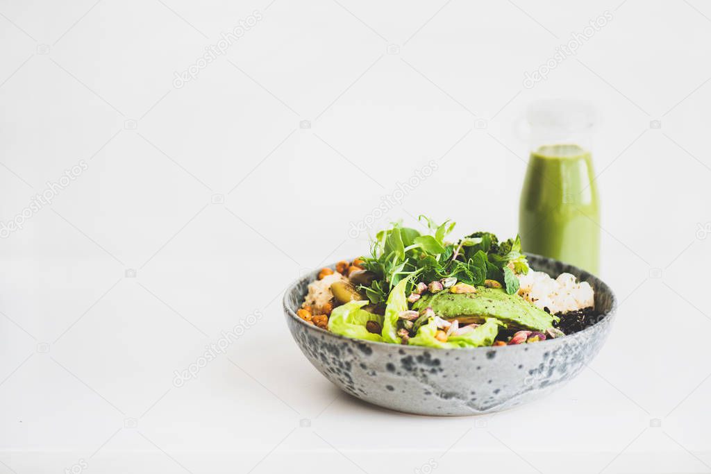 Healthy dinner or lunch. Vegan superbowl or Buddha bowl with homemade hummus, vegetable, fresh salad, beans, couscous and avocado and green smoothie in bottle over white background, copy space