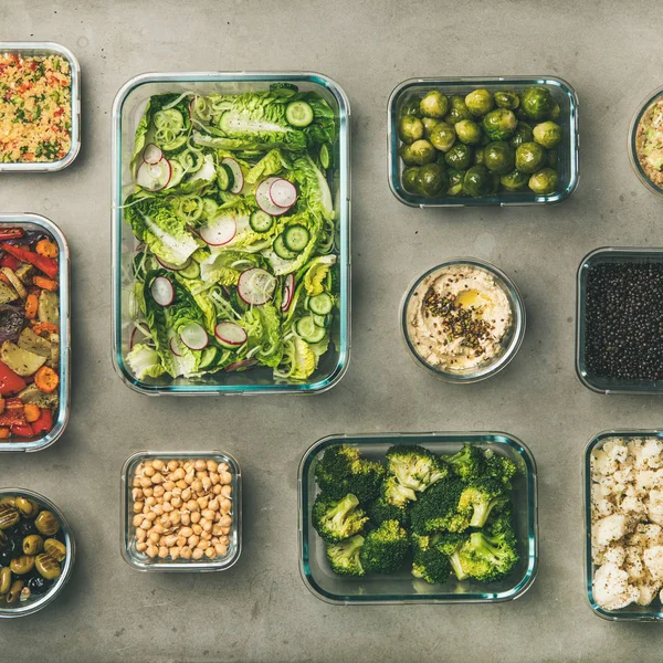 Healthy vegan dishes in containers. Flat-lay of vegetable salads, legumes, beans, fermented olives, sprouts, hummus dip, couscous for take-away lunch, top view, square crop. Spring menu, clean eating