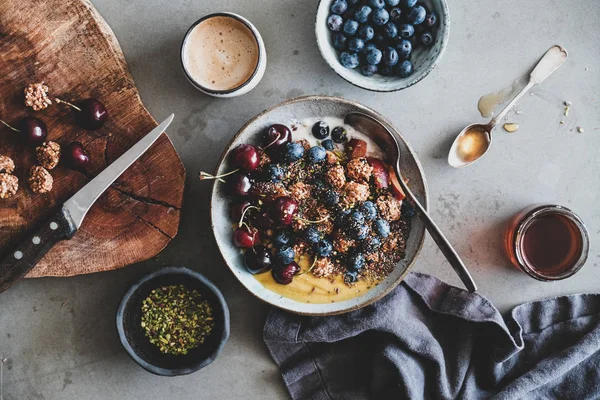 健康的なビーガンの朝食 キノアオートグラノーラココナッツヨーグルトボウルのフラットレイ 新鮮なフルーツ ナッツ ベリー コーヒーカップのグレーの背景 トップビュー クリーンな食べ物のコンセプト — ストック写真