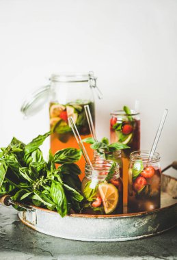 Taze ev yapımı çilek ve fesleğen limonata veya buzlu çay cam bardak ile çevre dostu cam plastik içermeyen pipetler rustik metal tepsi, arka planda beyaz duvar. Yaz soğuk ferahlatıcı meşrubat