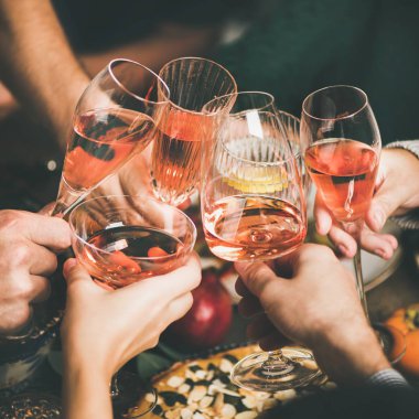 Geleneksel Noel veya Yeni Yıl tatili kutlama partisi. Arkadaşlar veya aile şölen ve ev yapımı aperatifler, kare ürün ile şenlikli Noel masasında gül şarabı ile gözlük clinking