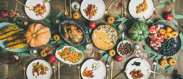 Thanksgiving, Friendsgiving holiday celebration. Flat-lay different meals at Thanksgiving Day table with turkey, pumpkin pie, roasted vegetables, fruit, rose wine, top view