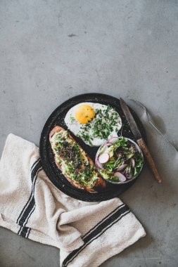 Sağlıklı kahvaltı. Otlar ve lahanalar, kızarmış yumurta ve gri beton arka plan üzerinde salata, üst görünüm, kopya alanı ile ekşi hamur ekmek üzerinde avokado tost Düz yatıyordu. Temiz beslenme, dengeli beslenme konsepti