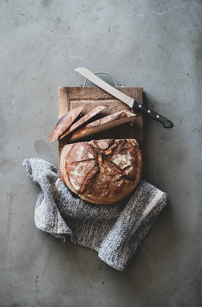 在灰色混凝土桌子背景 顶视图 垂直成分的质朴木板上 平铺新鲜出炉的酸面包面包和面包片 — 图库照片