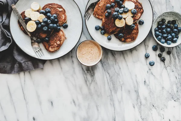 健康的な快適な朝食セット 新鮮なブルーベリーと蜂蜜とコーヒーのカップとバナナパンケーキのフラットレイ白い大理石のテーブルの背景 トップビュー コピースペース — ストック写真