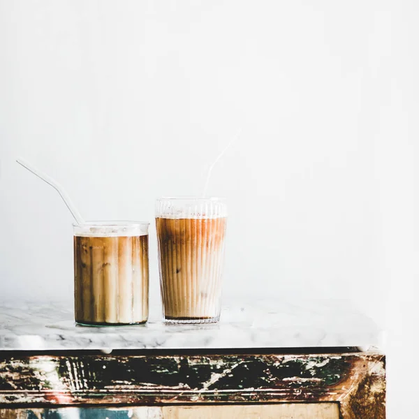 自制冰拿铁咖啡在玻璃杯与稻草在灰色大理石桌子上 白色墙壁的背景 复制空间 方形作物 夏季冷清饮概念 — 图库照片