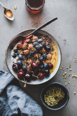 Sağlıklı kahvaltı. Taze meyve, bal, tohumlar, fındık, gri beton masa arka plan üzerinde çilek ile Quinoa yulaf granola hindistan cevizi yoğurt kase Düz yatıyordu, üst görünümü. Temiz beslenme, vejetaryen gıda konsepti