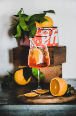 Portakallı Aperol Spritz aperatifi ve beton masa üzerinde çevre dostu cam pipetle cam aperatif, arka planda kutular olan beyaz duvar, seçici odaklanma, yakın plan. Yaz ferahlatıcı içecek konsepti