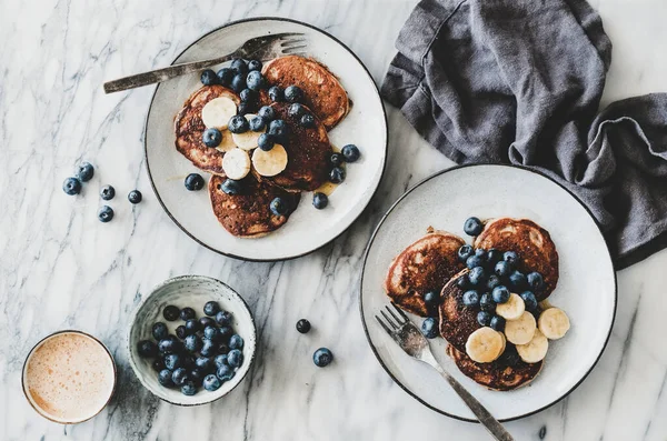 新鮮なブルーベリーと蜂蜜と白い大理石のテーブルの背景にコーヒーカップとバナナパンケーキのフラットレイ トップビュー 健康的な快適朝食セット — ストック写真