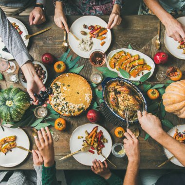 Şükran Günü, Arkadaş Verme bayramı kutlaması. Şükran Günü masasında hindi, balkabağı turtası, kavrulmuş sebze, meyve, gül şarabı, üst manzara, kare mahsulle yemek yiyen bir grup arkadaş.
