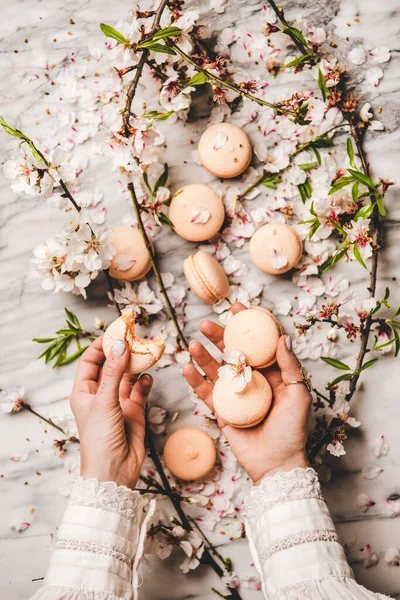 Colocación Plana Manos Mujeres Sosteniendo Dulces Galletas Macaron Sobre Flores —  Fotos de Stock