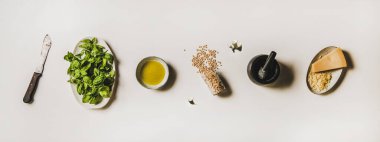 İtalyan pesto sosu pişirmek için gerekli malzemeler. Taze fesleğen yaprağı, zeytinyağı, çam fıstığı, sarımsak ve parmesan peyniri, beyaz arka plan, üst manzara. Geleneksel Iltalian Ligurian mutfağı