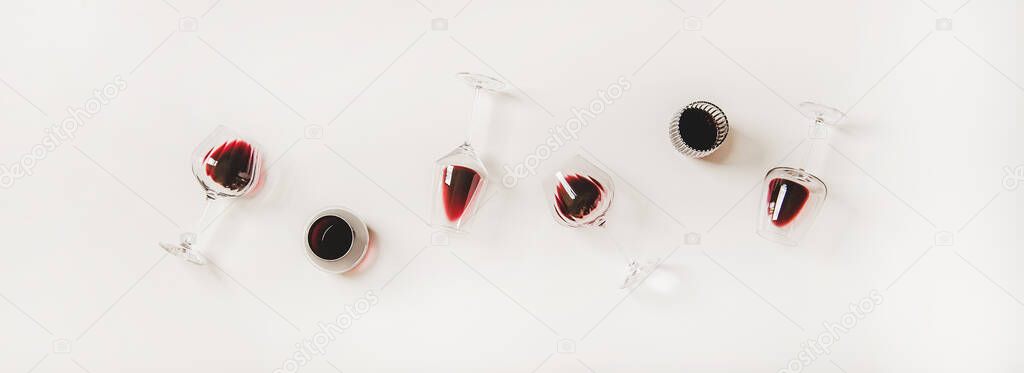 Red wine in glasses. Flat-lay of wine glasses with red wine in row over plain white background, top view. Wine tasting, winery, bar or Beaujolais Nouveau concept