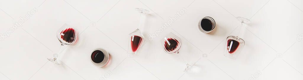 Red wine in glasses. Flat-lay of wine glasses with red wine in row over plain white background, top view, wide composition. Wine tasting, winery, bar or Beaujolais Nouveau concept